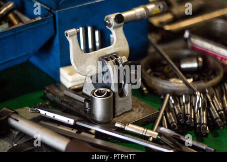 Micrometer and other tools for drilling and cutting metal lie on the table, close-up, manufacturing Stock Photo