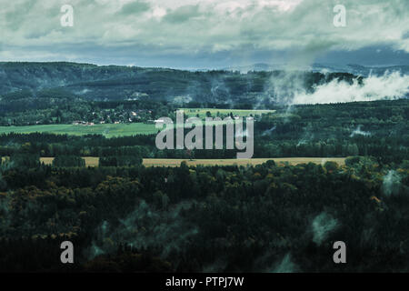 Deadpan dark misty rainy morning landscape with the sand rocky montains in Czech Saxon Switzerland in autumn colors. Stock Photo