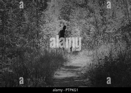 A man in a black mask takes the child to the forest, kidnapping the child, theft, human trafficking, black and white Stock Photo