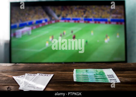On the table, betting tickets and euro money, in the background on the TV is football Stock Photo