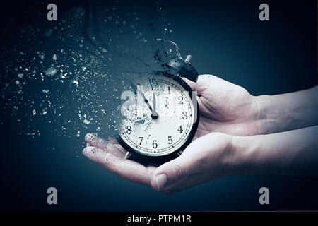 Concept of passing away, the clock breaks down into pieces. Hand holding analog clock with dispersion effect Stock Photo