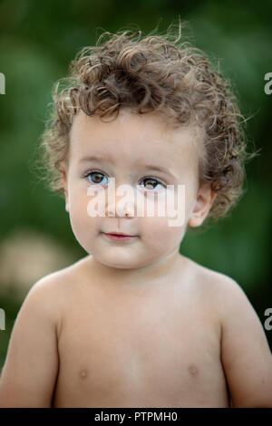 Beautiful baby with curly hair in the garden without t-shirt Stock Photo