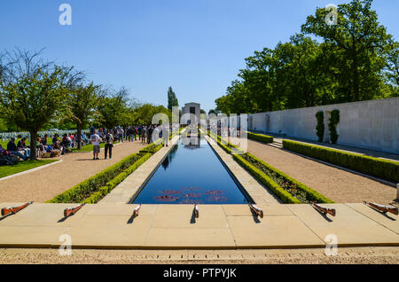 Reflecting pool leading to chapel, and memorial wall at the Cambridge American Cemetery and Memorial. Memorial Day event. Grave headstones and flags Stock Photo