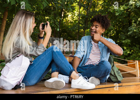 Happy young multiethnic couple spending time together at the park, taking photo of each other Stock Photo