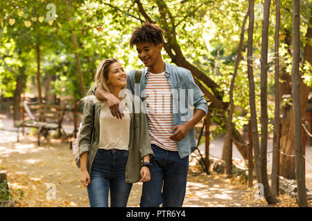 Happy young multiethnic couple spending time together at the park, walking, hugging Stock Photo