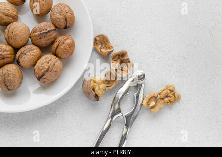 Walnuts on a plate, metal nutcracker on white background Stock Photo