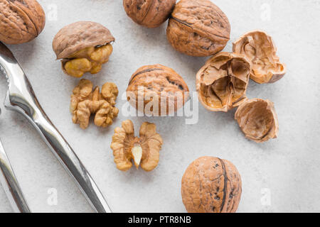 Some walnuts and silver nutcracker on grey background Stock Photo