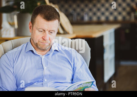 Man in business attire reading a magazine in a co-working space that functions as his office Stock Photo