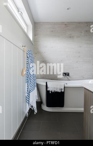 Striped towel and backbrush beside freestanding bath in coastal home Stock Photo