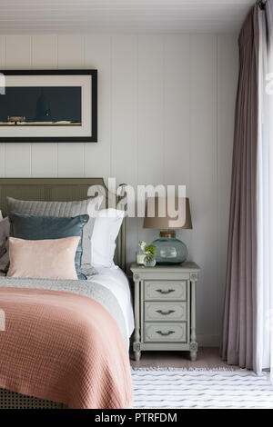 Peach quilt on double bed with gold lamp on bedside table Stock Photo