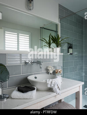 Large mirror above wash basin with metro tiles in coastal home Stock Photo