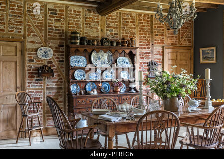 Decorative chinaware on antique wooden dresser with table and chairs in restored 16th century farmhouse Stock Photo