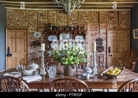 Decorative chinaware on antique wooden dresser with table and chairs in restored 16th century farmhouse Stock Photo