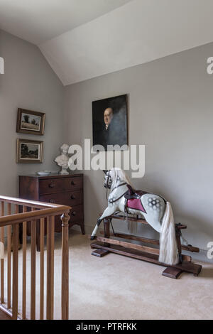 Antique rocking horse and chest with wooden banisters on landing in restored 16th century farmhouse