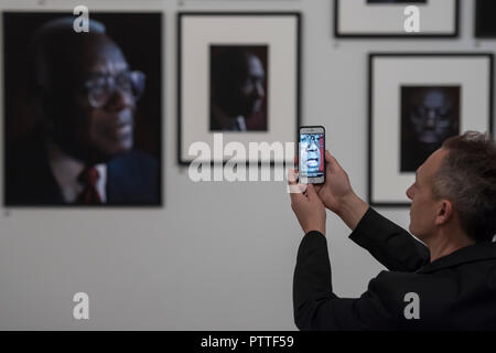 London, UK. 10th October, 2018. Using the app that allows you to see the persons interview when pointed at their portrait - Black is the New Black: Portraits by Simon Frederick at National Portrait Gallery, London, the Gallery’s largest acquisition of portraits of Afro-Caribbean (on display until 27 January 2019). Credit: Guy Bell/Alamy Live News Stock Photo