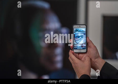 London, UK. 10th October, 2018. Using the app that allows you to see the persons interview when pointed at their portrait - Black is the New Black: Portraits by Simon Frederick at National Portrait Gallery, London, the Gallery’s largest acquisition of portraits of Afro-Caribbean (on display until 27 January 2019). Credit: Guy Bell/Alamy Live News Stock Photo