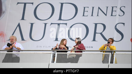 Frankfurt, Germany. 11th October, 2018. 11 October 2018, Hessen, Frankfurt Main: Visitors to the Frankfurt Book Fair take a break in front of a film poster with the inscription 'Death of an Author'. The world's largest book show takes place until 14 October. Photo: Arne Dedert/dpa Credit: dpa picture alliance/Alamy Live News Stock Photo