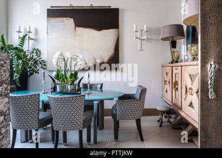 Large wooden sideboard and modern art in dining room with upholstered chairs Stock Photo