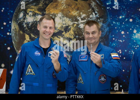 Expedition 57 crew member cosmonaut Alexey Ovchinin of Roscosmos, right, and Nick Hague of NASA hold up launch keys during a tour of the Baikonur Cosmodrome Museum at the Baikonur Cosmodrome October 6, 2018 in Baikonur, Kazakhstan. The two are scheduled to launch on October 11th and will spend the next six months living and working aboard the International Space Station. The mascots will be mounted over their heads in the Soyuz MS-10 spacecraft to serve as “zero-G” indicators when they launch. Stock Photo