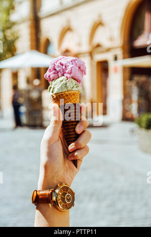 Woman Holding Green Pistachio And Pink Raspberry Ice Cream Cone In Hand Stock Photo