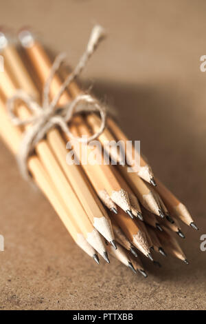 a stack of graphite pencils tied with rope on wooden background ...