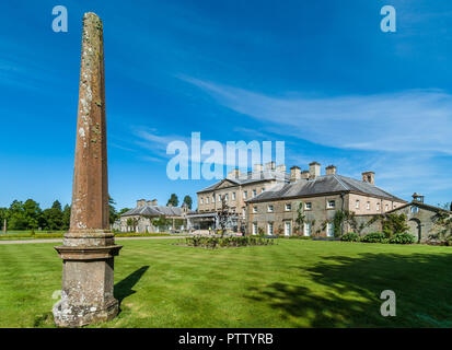 Cumnock, Ayrshire, Scotland, UK - June 18, 2012: Molded stone obelisk in garden of brown stone Dumfries House, Green lawn and blue sky. Stock Photo