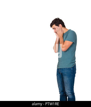 Side view of a disappointed and stressed young man hands on cheeks looking down isolated over white background with copy space. Sad feeling, negative  Stock Photo