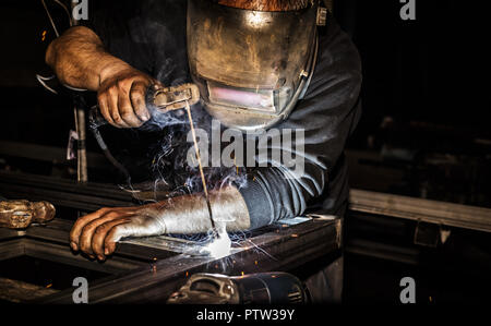 Professional welder in mask welds steel with electric torch tool Stock Photo