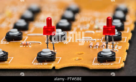 Disassembled telephone. Red LED diodes and gray buttons. Circuit board with plastic pushbuttons. Electronic components on dismantled VoIP phone keypad. Stock Photo