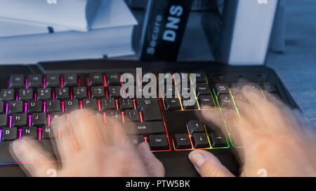 Colored computer keyboard. Human hands in motion. Close-up of typing fingers of hacker, spy or censor. Book detail. Secure DNS writing on background. Stock Photo