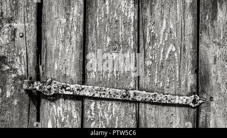 Old rustic wicket in black and white detail. Striped wooden texture. Artistic close-up of vintage wood door and rusty metal hinge. Abstract background. Stock Photo