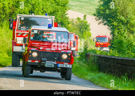 French fire engines on call on country lane.
