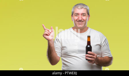 Handsome senior man drinking beer bottle over isolated background very happy pointing with hand and finger to the side Stock Photo