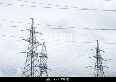 Three electric towers on the sky background, tension Stock Photo