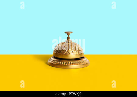 Ornate traditional golden service bell on yellow counter Stock Photo