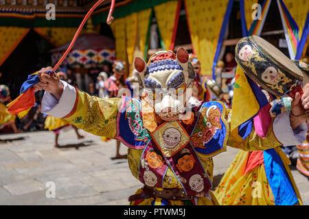 Buddhist Monk dancing and holding a drum at colourful mask dance at yearly buddhism Paro Tsechu festival in Bhutan monastery temple location. Stock Photo