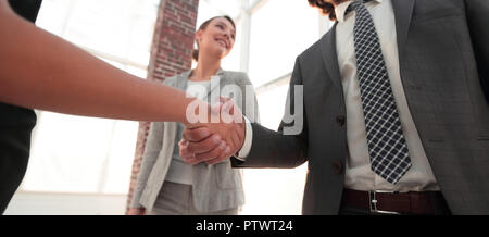 Businesspeople  shaking hands against room with large window loo Stock Photo