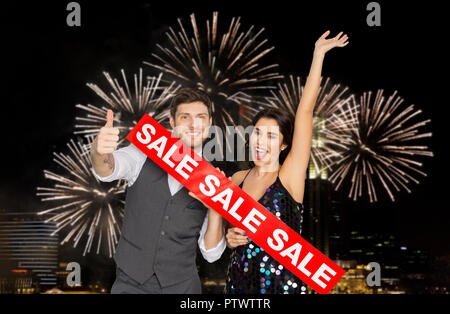 happy couple with red sale sign showing thumbs up Stock Photo