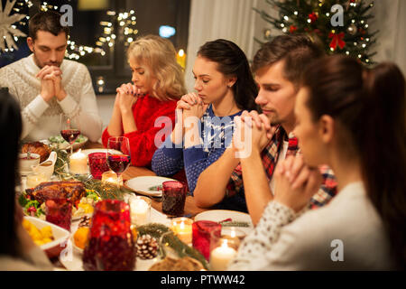 friends having home christmas dinner and praying Stock Photo