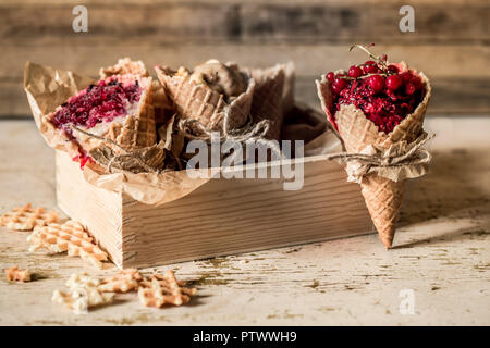 homemade ice cream in a waffle cone with berries on wooden background wooden box ,place for text Stock Photo