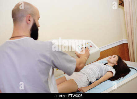 the doctor examines a young woman on a bone densitometer. Stock Photo