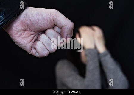 Male fist on black background, in the background a crying girl Stock Photo