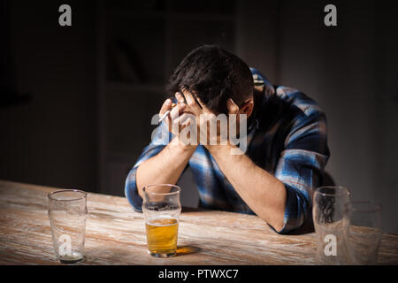 drunk man drinking alcohol and smoking cigarette Stock Photo