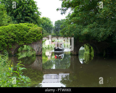 A narrow boat approaches a picturesque bridge on the River Way near Godalming in Surrey, England. Stock Photo