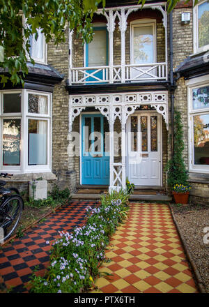 Geometric pavers, colorful doors and gingerbread trim on pair of Victorian terrace houses Stock Photo