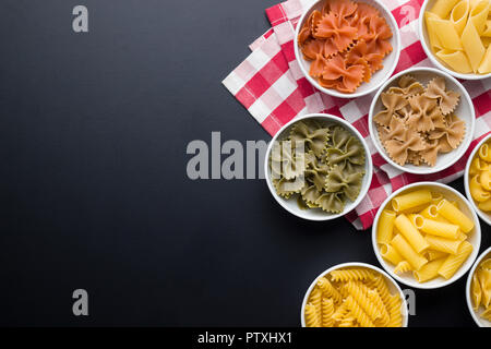 Various types of italian pasta in bowl on black background. Stock Photo