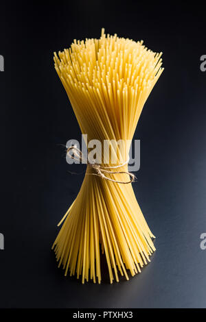 Uncooked spaghetti pasta on black background. Stock Photo