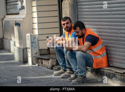 Istanbul, Turkey, September 2018: Still life of two Turkish workers who play with their mobile phones during breakfast break in the pedestrian zone. Stock Photo