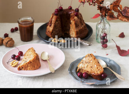 Apple pie with nuts, decorated with salted caramel and small red apples. Rustic style. Stock Photo