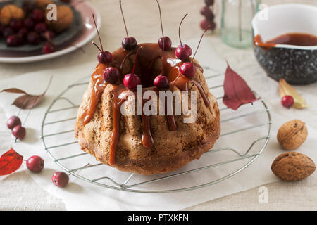 Apple pie with nuts, decorated with salted caramel and small red apples. Rustic style. Stock Photo